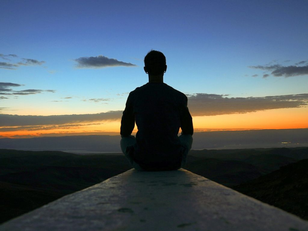 Ein Mann meditiert vor der untergehenden Sonne